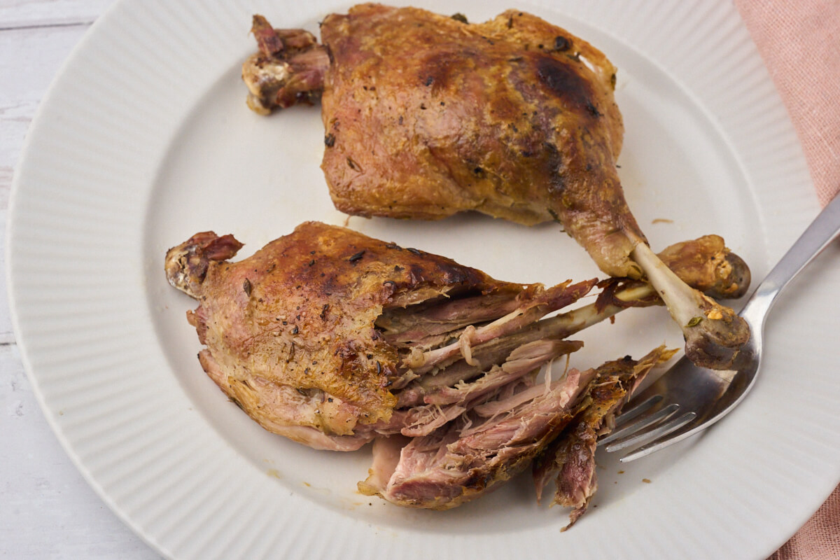 tallerken med andelår der er confiteret i sous vide, hvor kødet er trukket af benet med en gaffel.