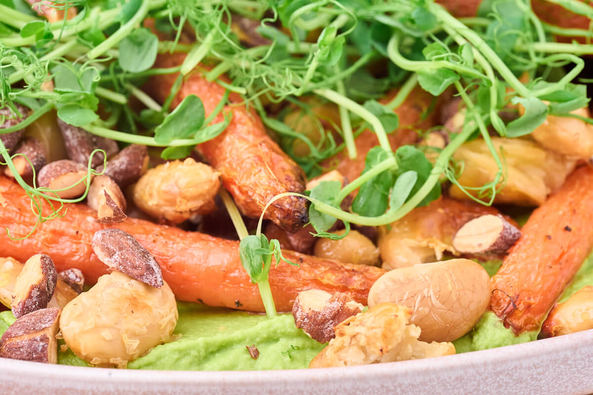grøn ærte/bønnepuré på fad med bagte gulerødder og butterbeans som vegetarisk aftensmad.