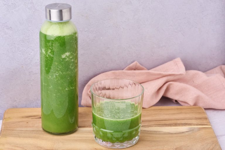 grøn juice med grønkål og pære i flaske og glas klar til at drikke.