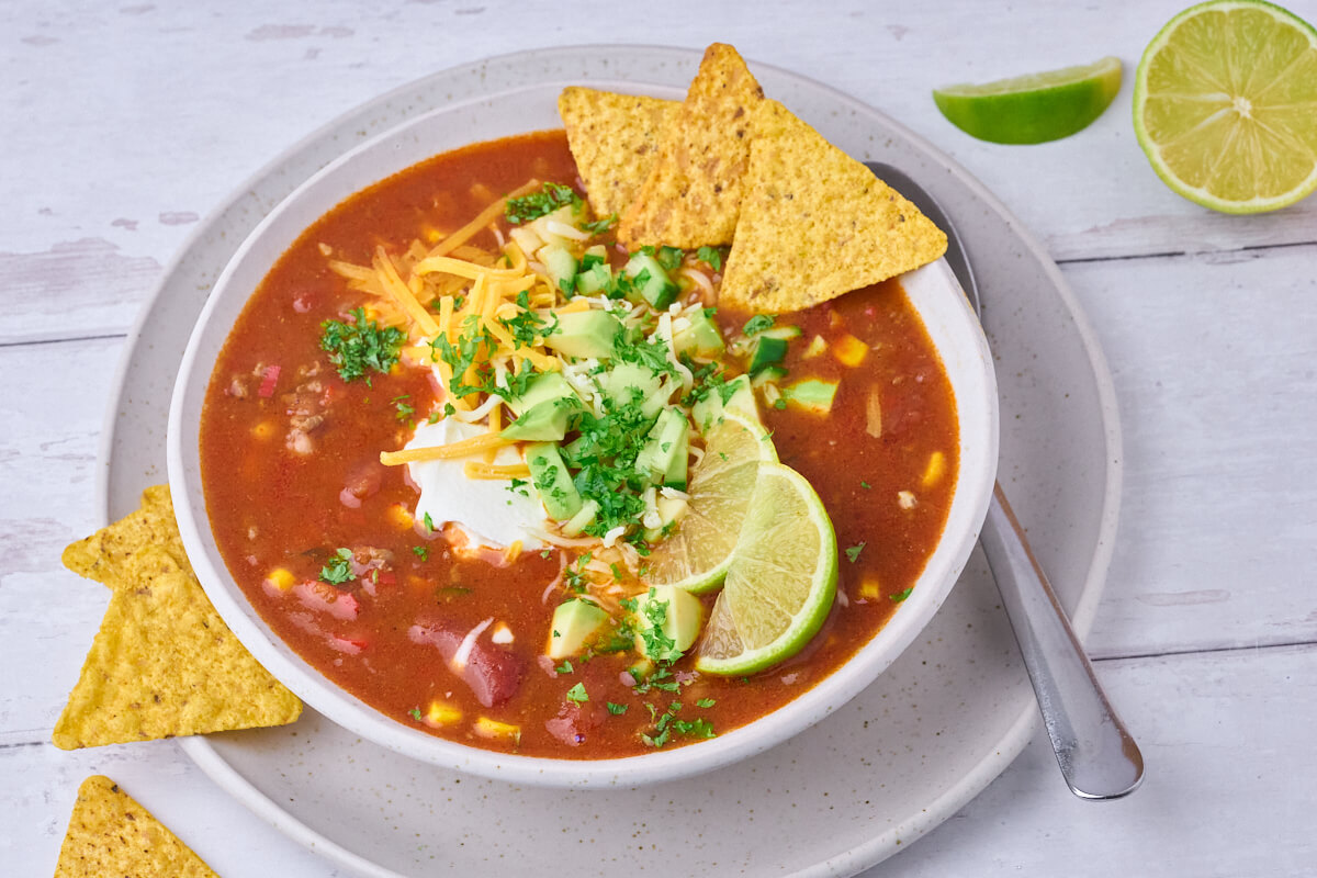 nem og lækker mexicansk tacosuppe med hakket oksekød, majs, bønner sammen med creme fraiche, avocado og tortillachips.