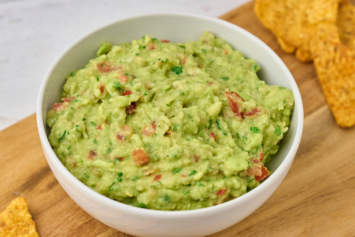 hjemmelavet guacamole i skål med tortilla chips ved siden af.