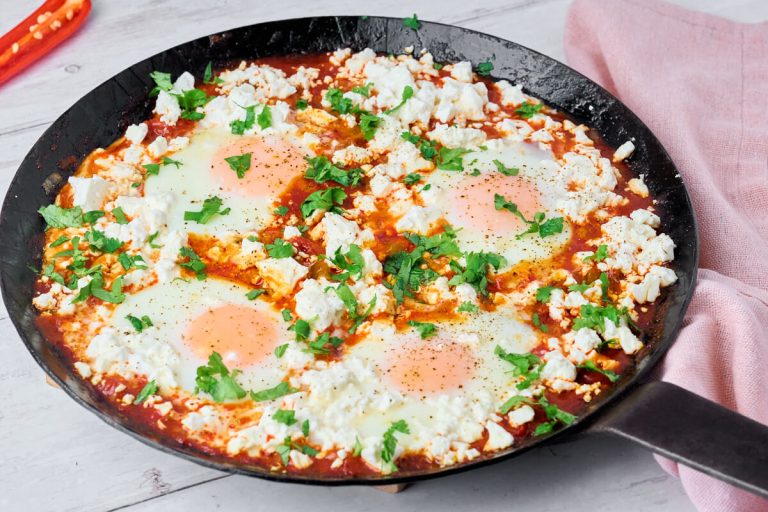shakshuka i støbejernspande med feta og frisk koriander på toppen.
