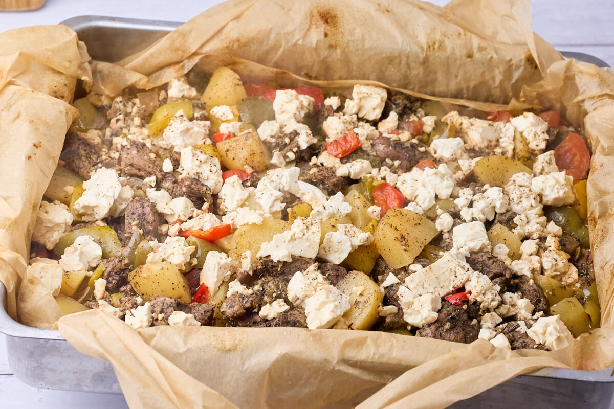 græsk kleftiko med lam, kartofler, grøntsager og feta i fad.