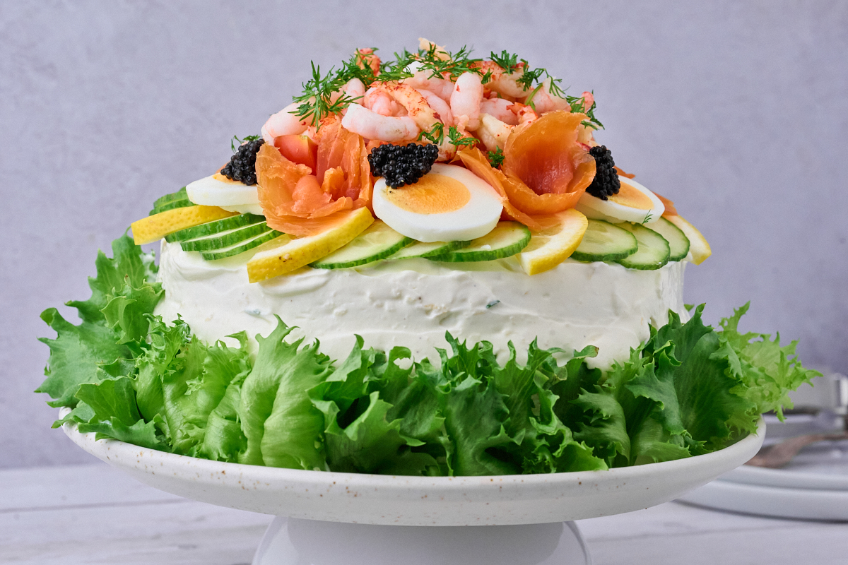 Smörgåstårta som er en Svensk fiskelagkage pyntet med rejer, æg, salat, laks og krebsehaler på serveringsfad.