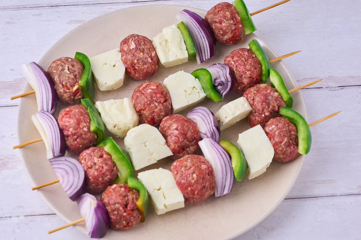 rå grillspyd med kødboller, grillost, grøn peberfrugt og rødløg.