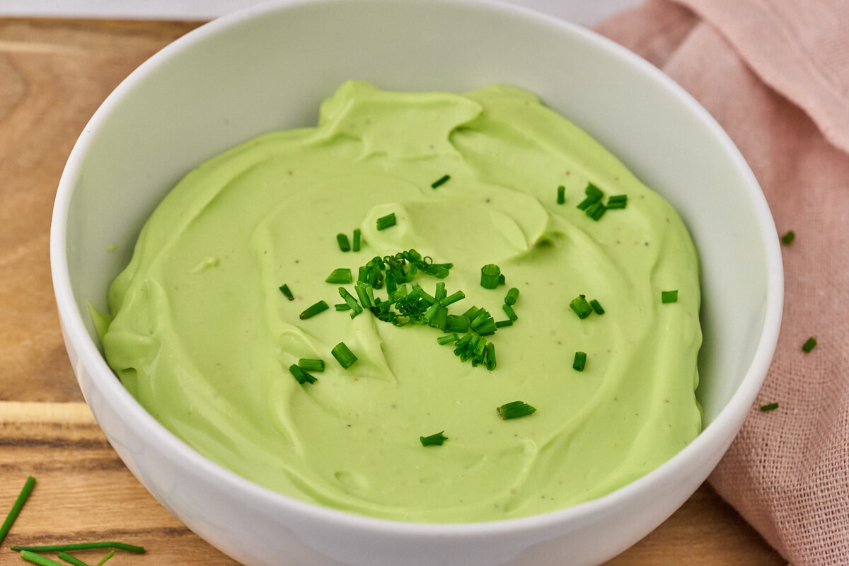 Hjemmelavet purlรธgsmayonnaise i skรฅl med frisk purlรธg pรฅ toppen.