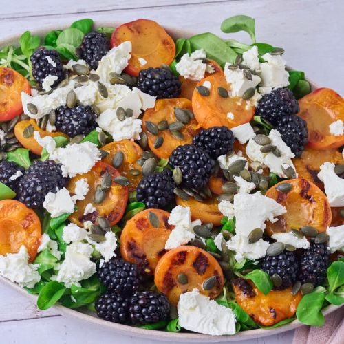 salat med grillede abrikoser, feta og brombær på salatfad.