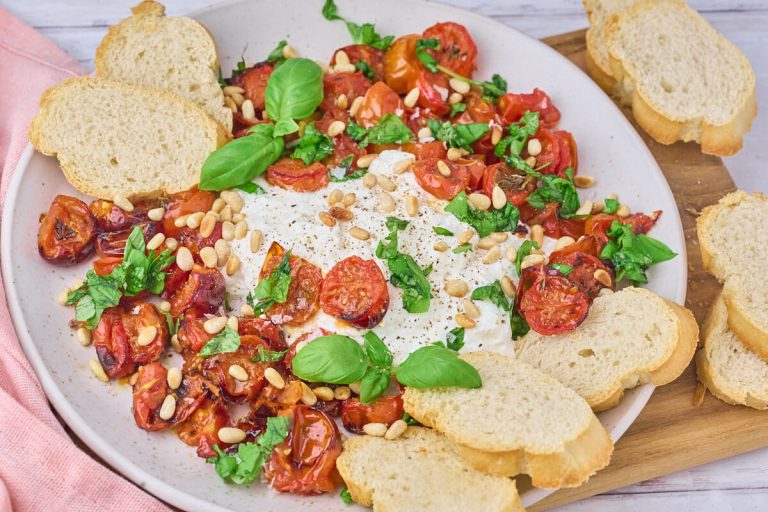 Burrata med bagte tomater, pinjekerner og basilikum serveret med brød til.