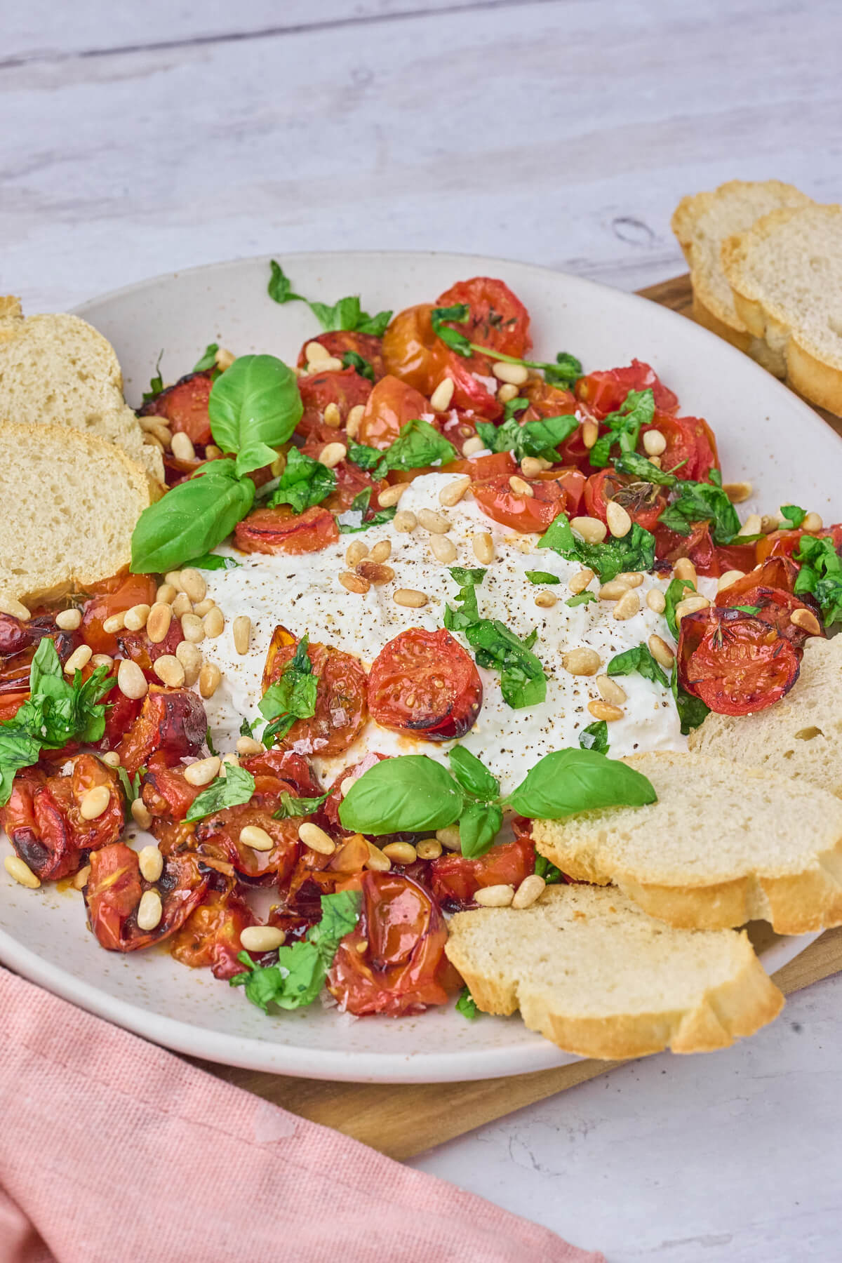 burrata med bagte cherrytomater og frisk basilikum og pinjekerner.