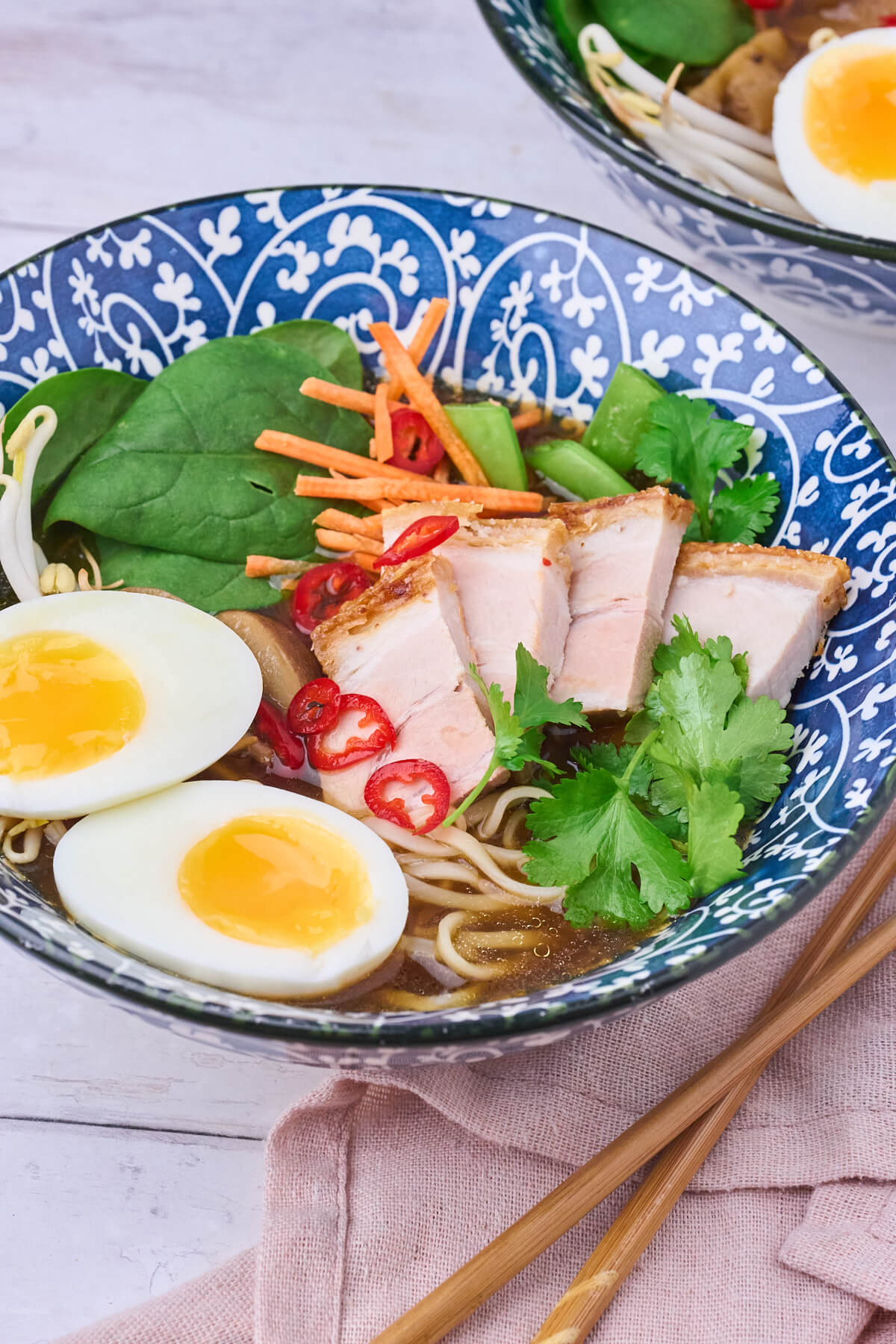 skål med japansk ramen suppe med rester af ribbensteg, smilende æg og grønt.