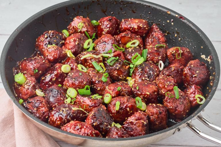 Sticky kyllingefrikadeller med grøntsager i pande med hakkede forårløg på toppen.