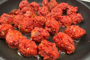 kyllingefrikadeller med grøntsager på panden.