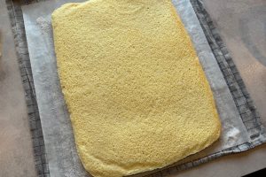 færdigbagt rouladebund vendt ud på bagepapir med sukker.