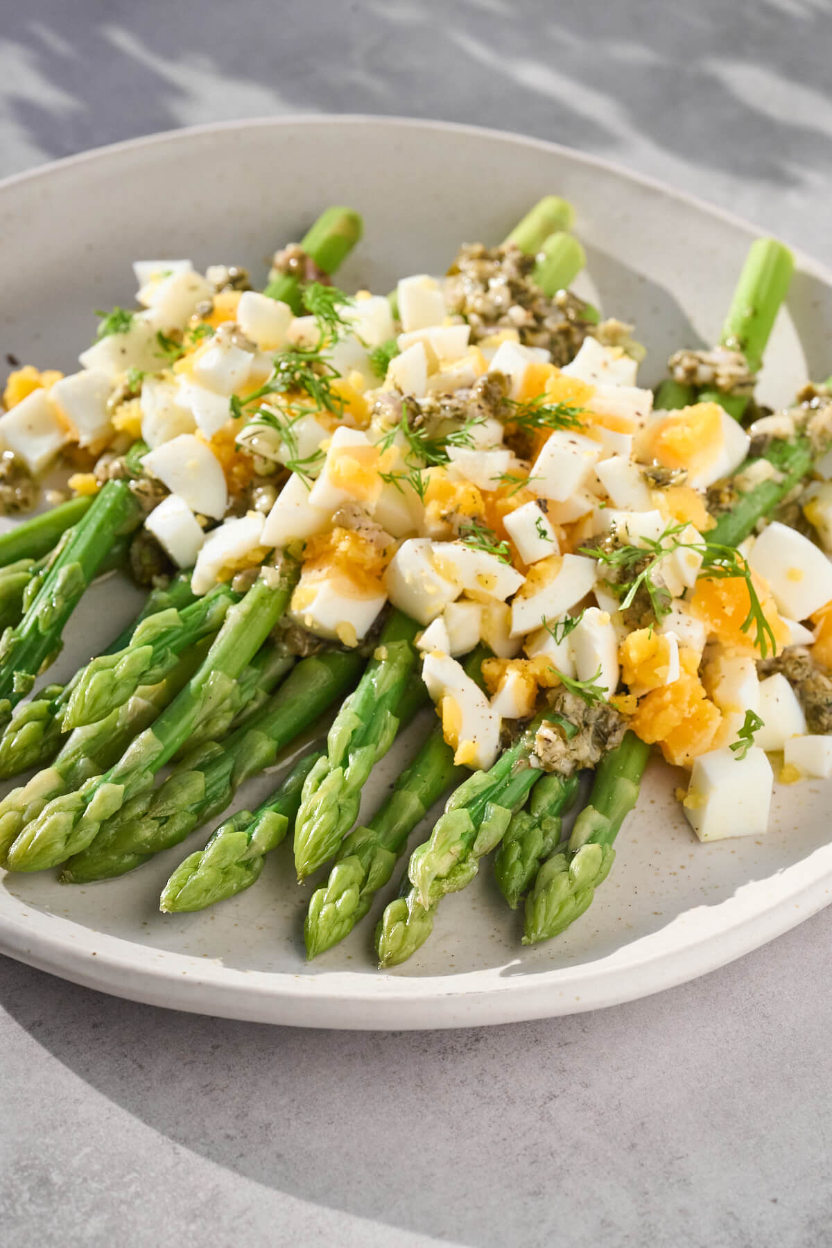 grønne asparges med hakkede æg og kapersvinaigrette.