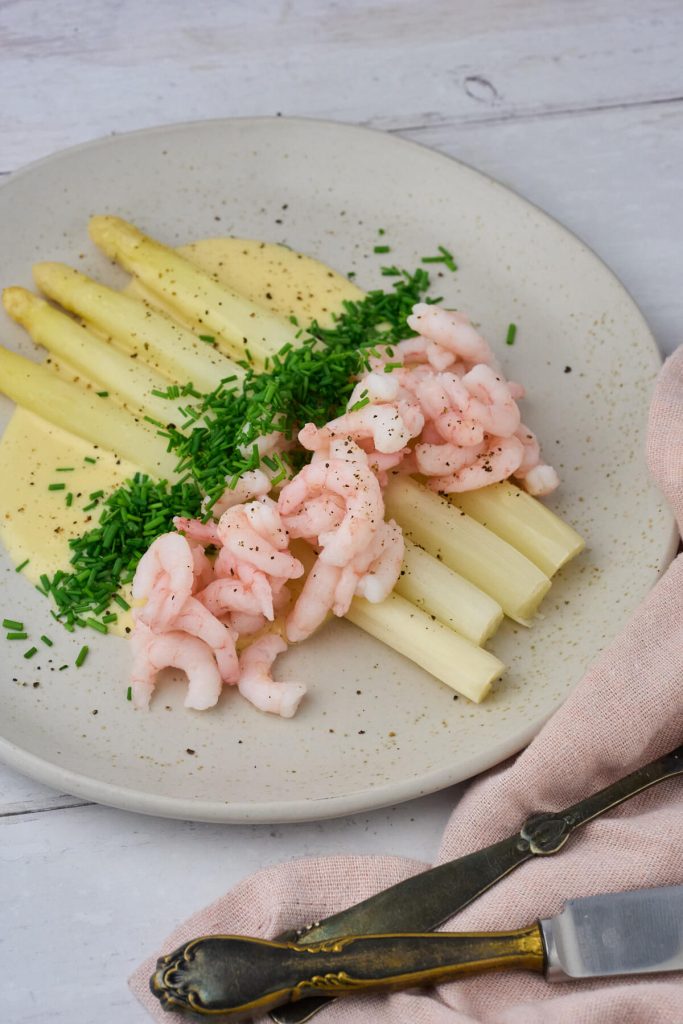 anretning med pocherede hvide asparges med beurre blanc og rejer samt purløg.