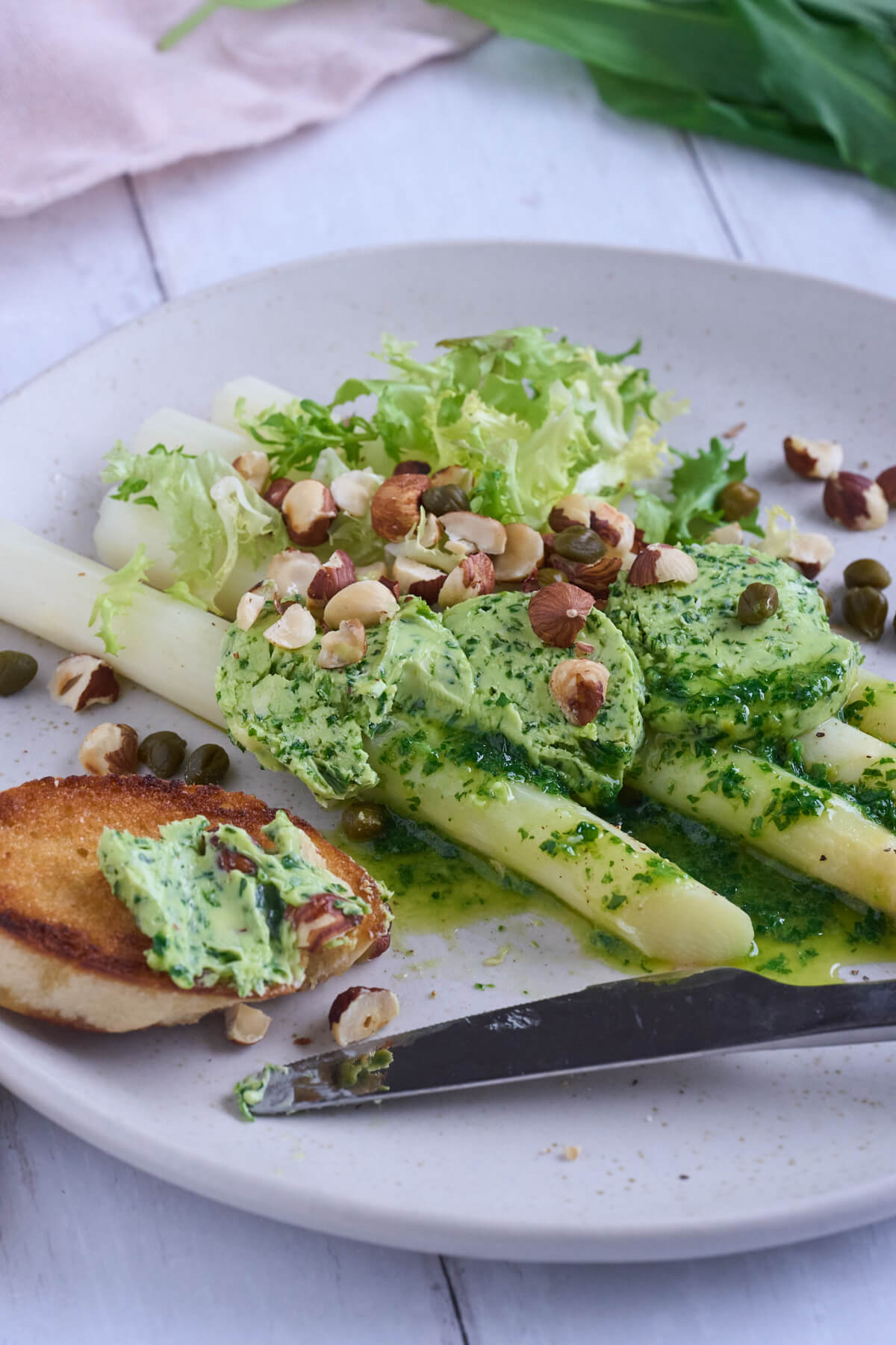hvide asparges med ramsløgssmør, ristede hasselnødder og brød.