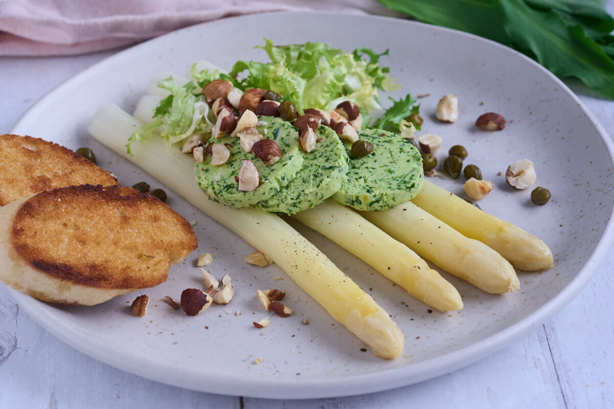 hvide asparges med ramsløgssmør og ristede hasselnødder samt kapers, salat og brød.