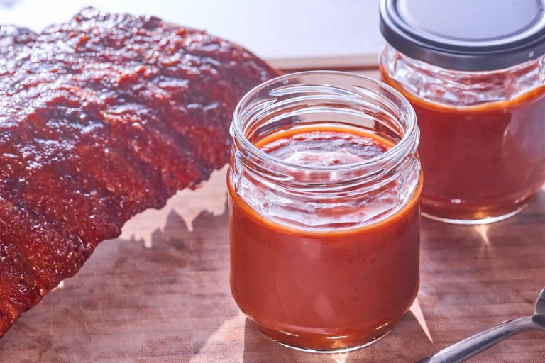 hjemmelavet barbecuesauce med bourbon i glas med spareribs.