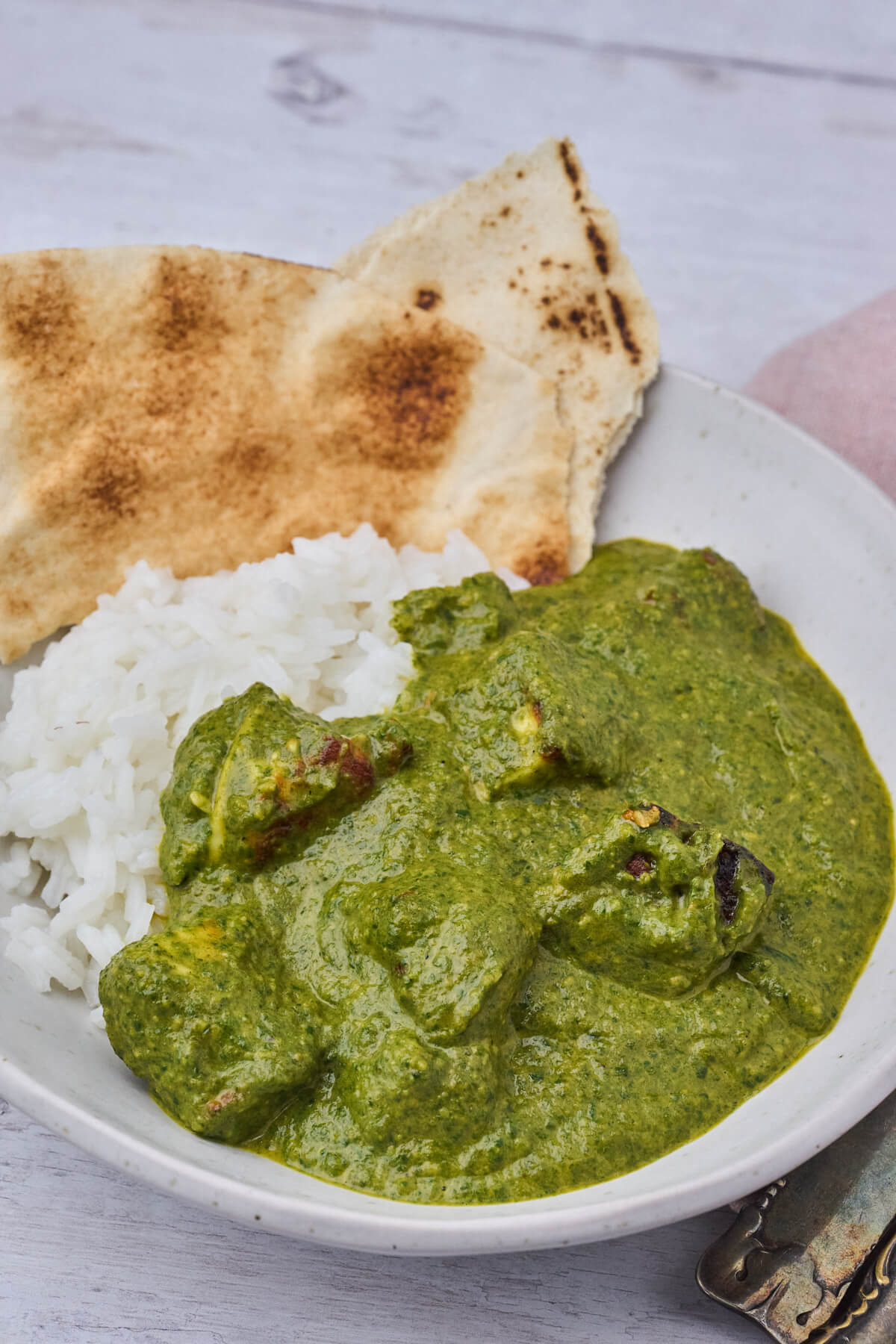 grøn palak paneer serveret som indisk mad i skål med ris og brød.